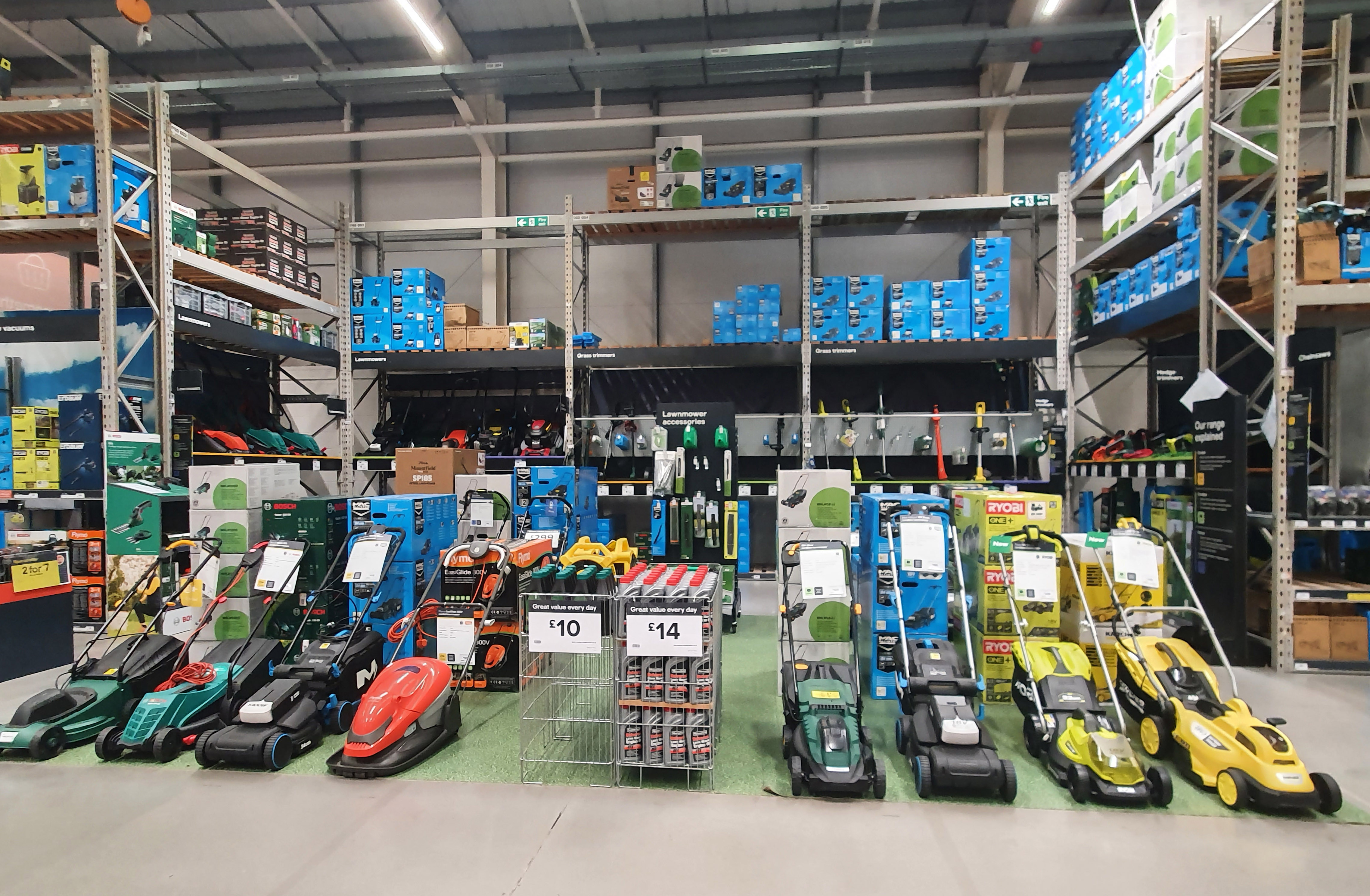 Rows of assembled lawn mowers lined up on display in a retail store